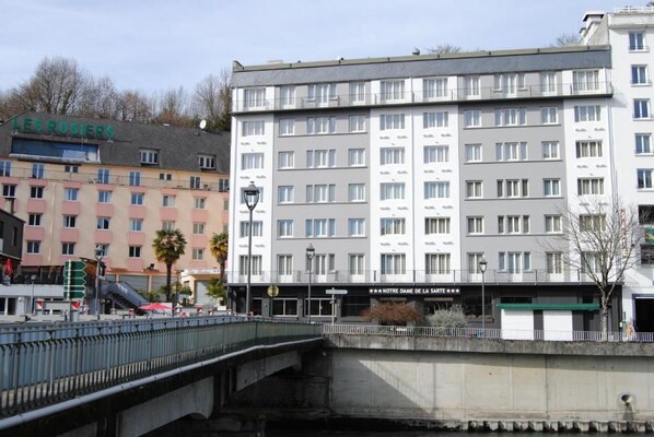 Un hotel de varios pisos con una fachada moderna, balcones y un letrero que dice 'Notre Dame de la Sainte'.