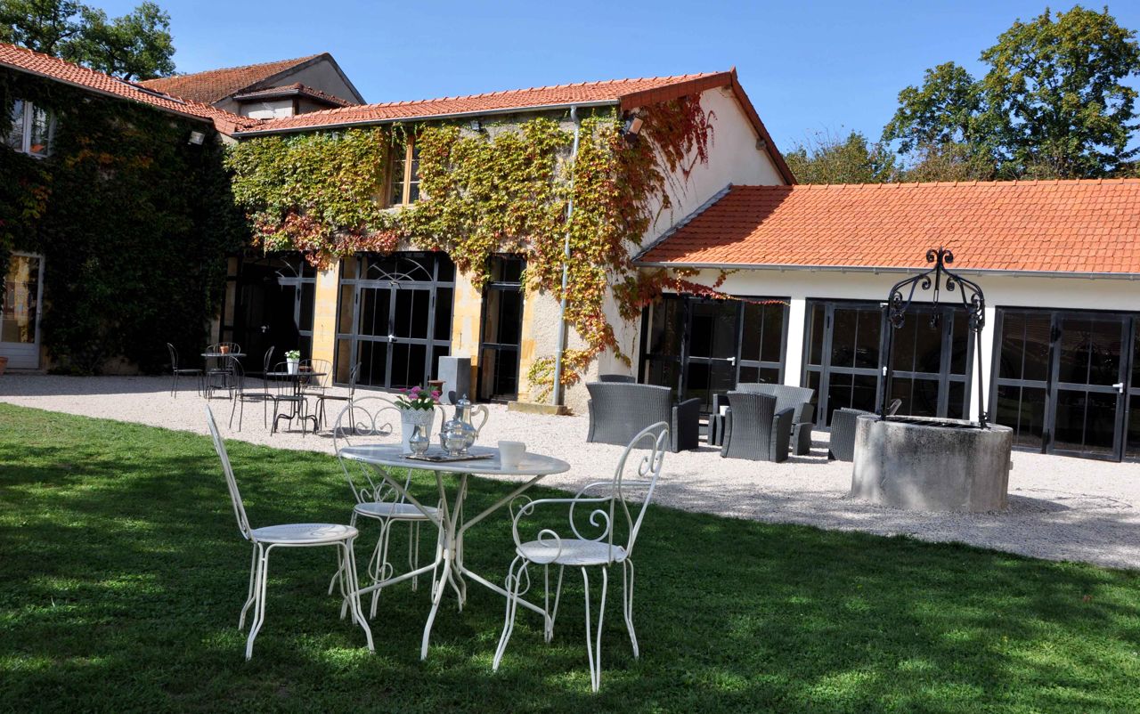 Un patio con asientos al aire libre, una zona techada y un edificio con tejado de baldosas.