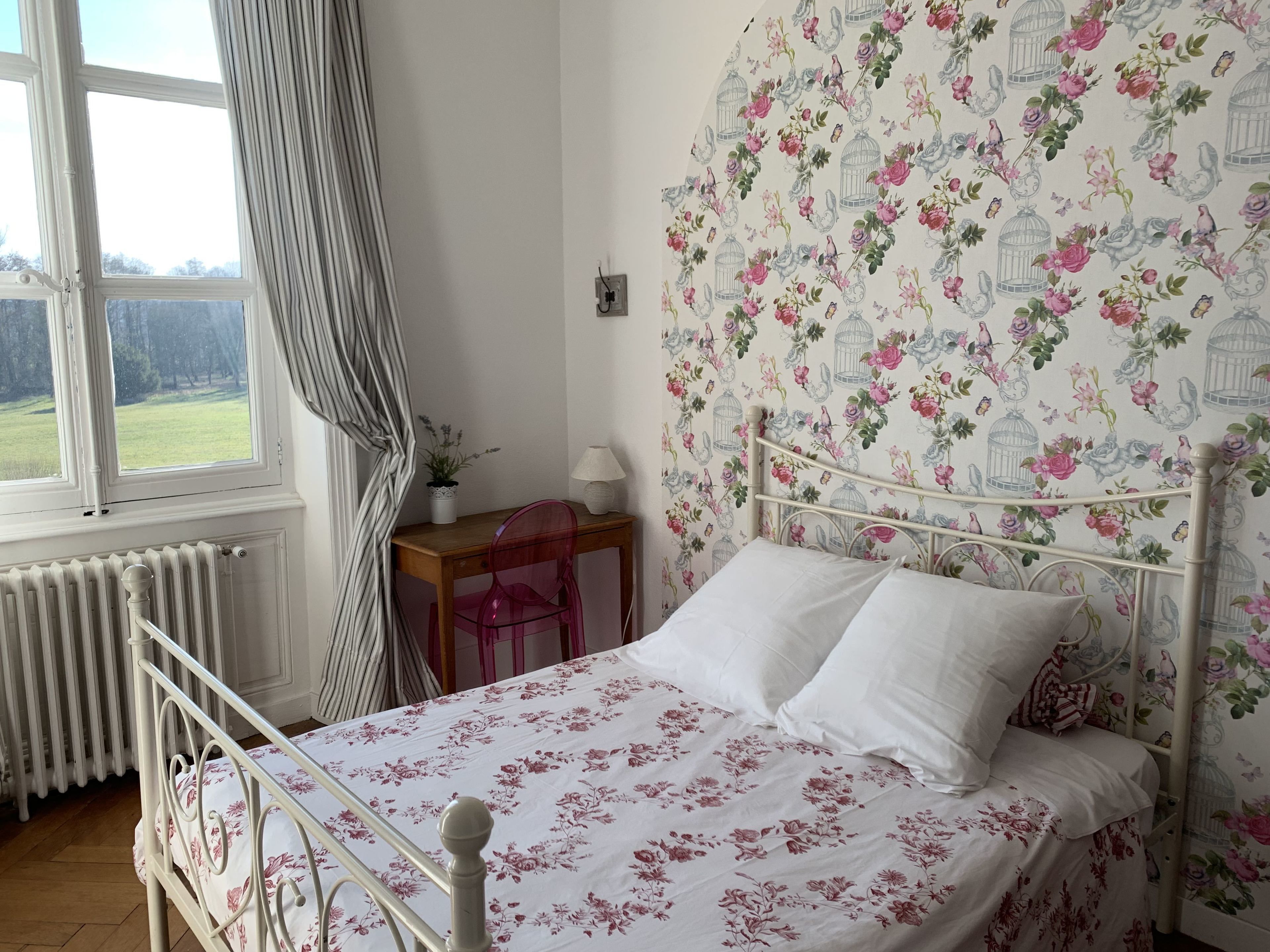 A bedroom with a bed, a desk, a chair, and a radiator.