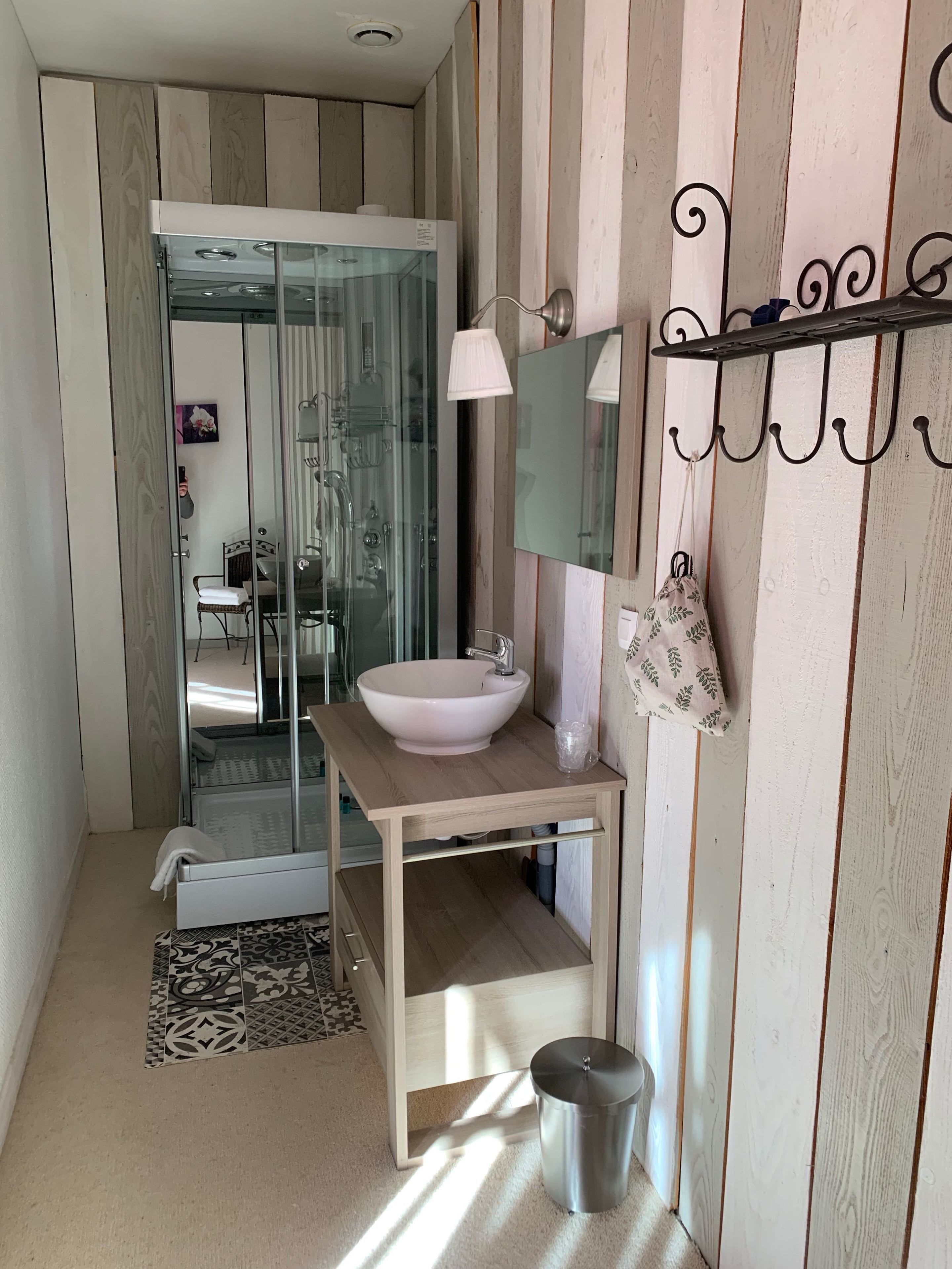 Une salle de bain moderne avec une douche en verre, un meuble-lavabo en bois et un porte-serviettes suspendu.