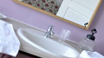 A bathroom with a sink, mirror, and a door leading to a bedroom.