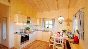 A wooden cabin interior with a kitchen, dining area, and a cozy seating space. - Lamplhof (Rimsting)