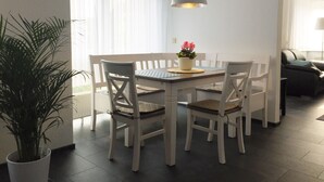 A dining area with a table, chairs, a hanging light fixture, and a potted plant.