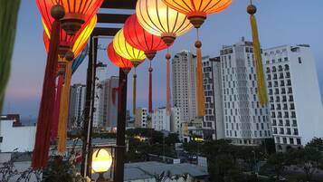A row of colorful lanterns hanging outdoors with a cityscape in the background.