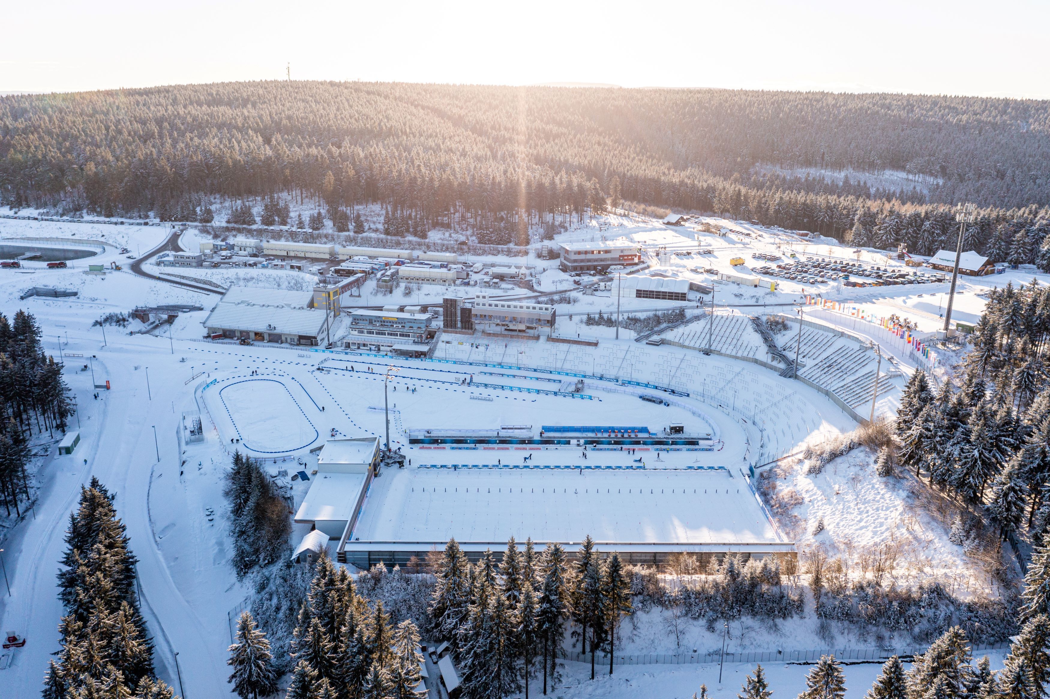 A snow-covered ski resort with a large building, ski slopes, and a parking area.