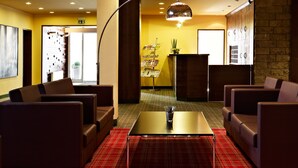 Eine Lobby mit einer Rezeption, einer Sitzgelegenheit und einem Check-in-Schalter.