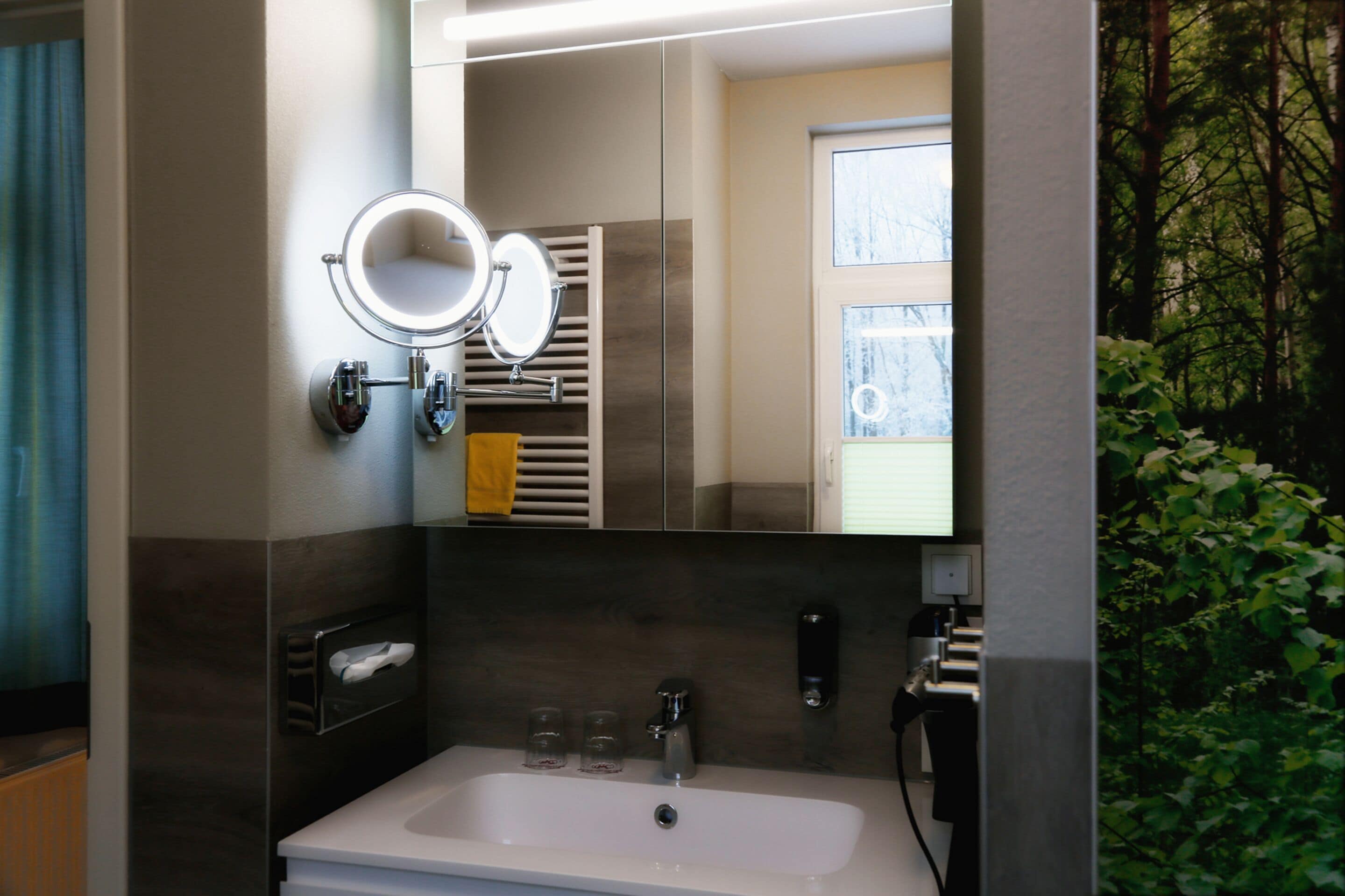 Un baño moderno con un espejo grande, un lavabo y un perchero para toallas.
