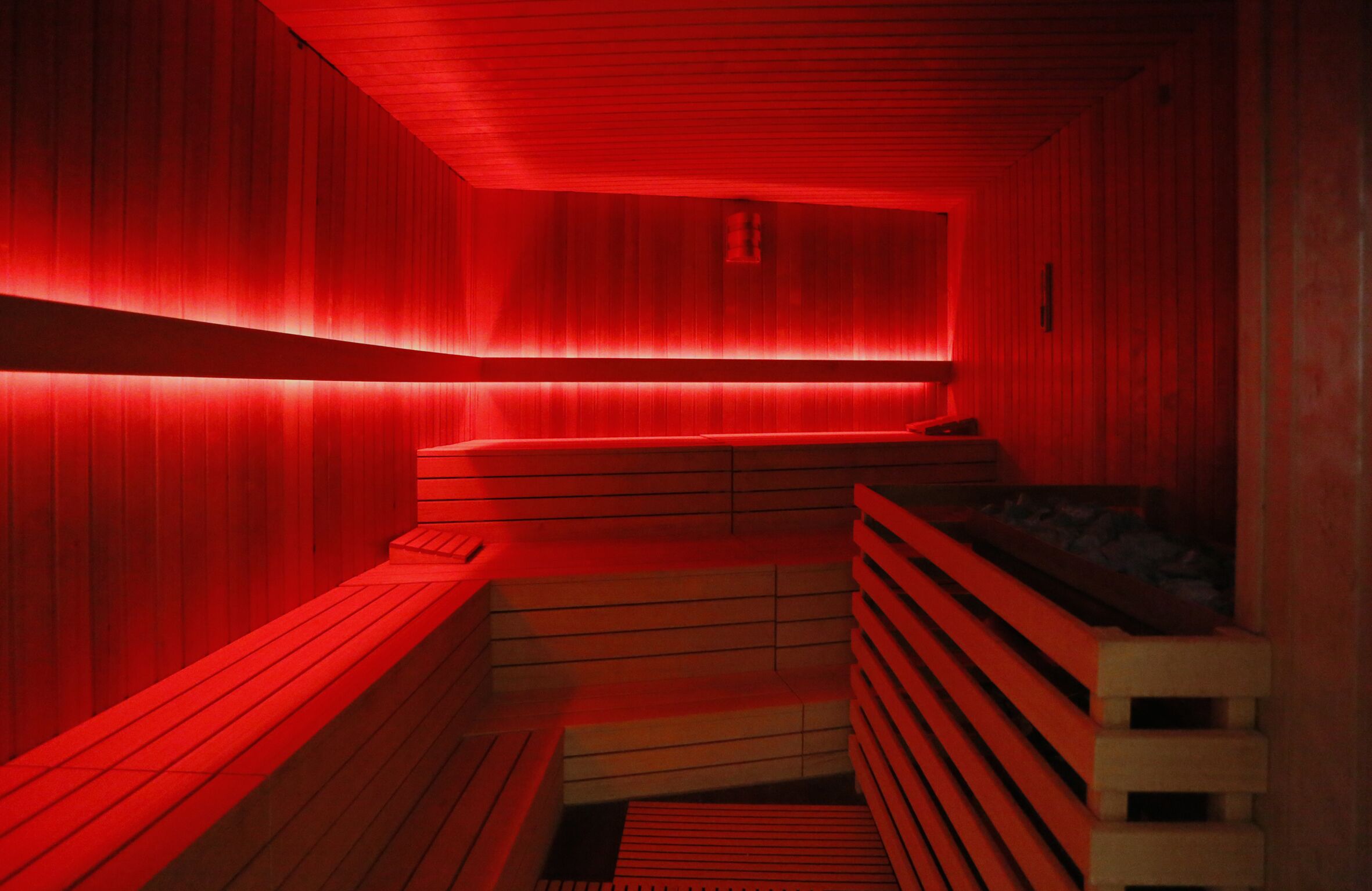 Un sauna avec des bancs en bois et un banc doté d’un matelas.