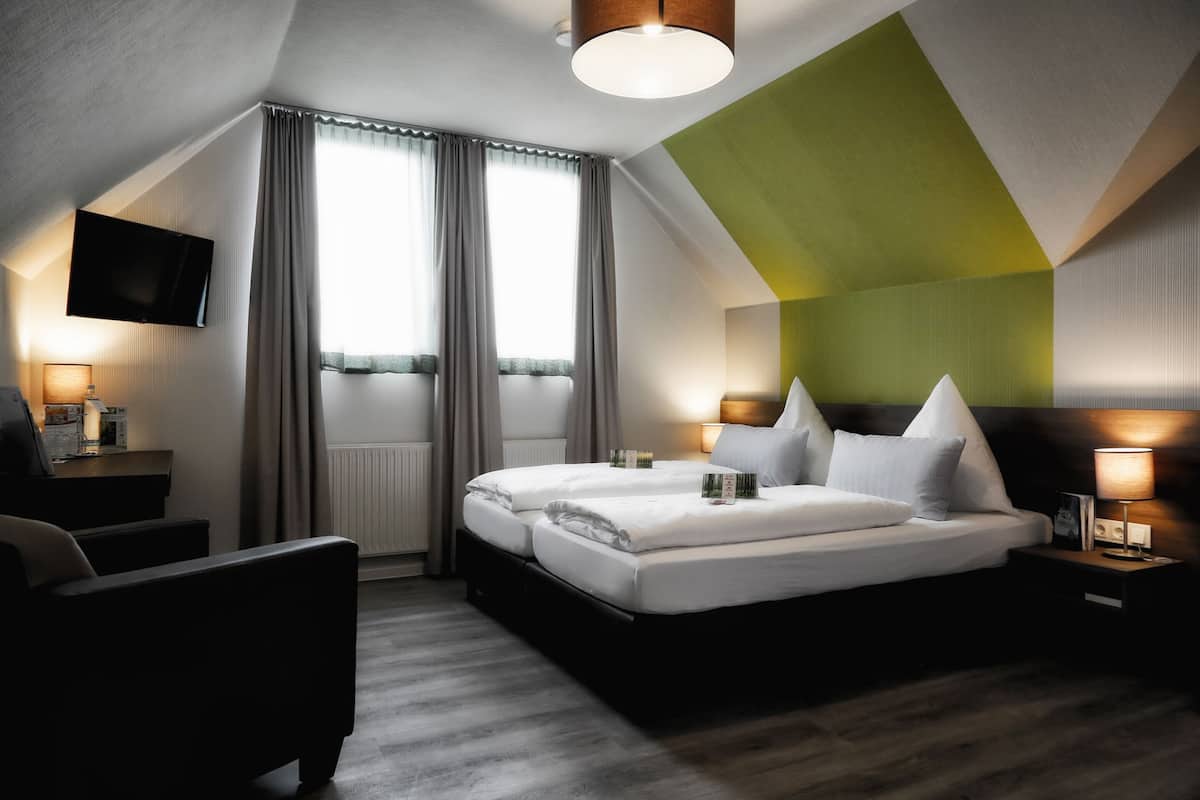 A modern hotel room with a large bed, two bedside tables, a flat-screen TV, and a seating area.