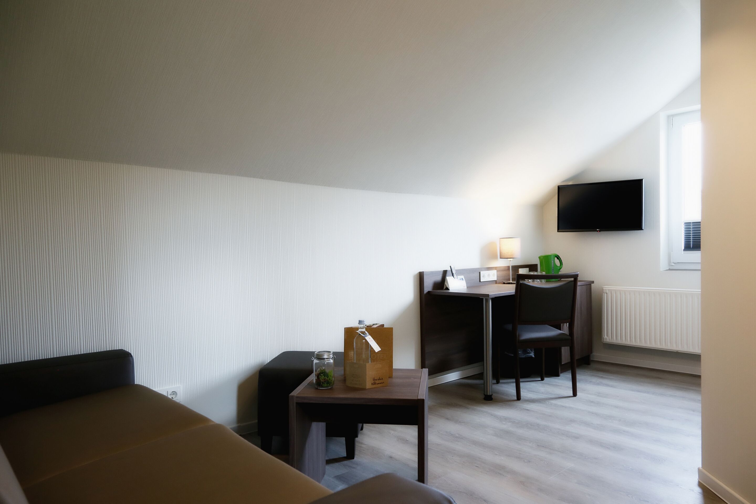 A hotel room with a bed, a desk, a chair, a TV, and a window.