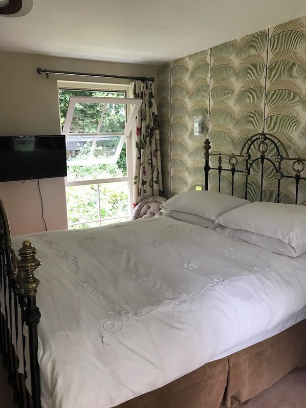 A bedroom with a bed, curtains, a television, and a window. - St Mary's Mount (Ulverston)