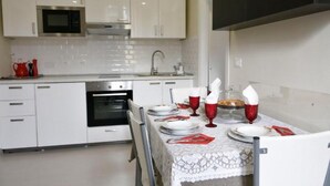 A modern kitchen with white cabinets, a microwave, an oven, and a dining table set with plates, glasses, and cutlery. - 5 Tourist House Apartment Centre Bologna (Bologna)