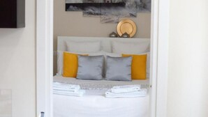 A neatly made bed with white linens, two pillows, and a folded towel on a white headboard. - 5 Tourist House Apartment Centre Bologna (Bologna)