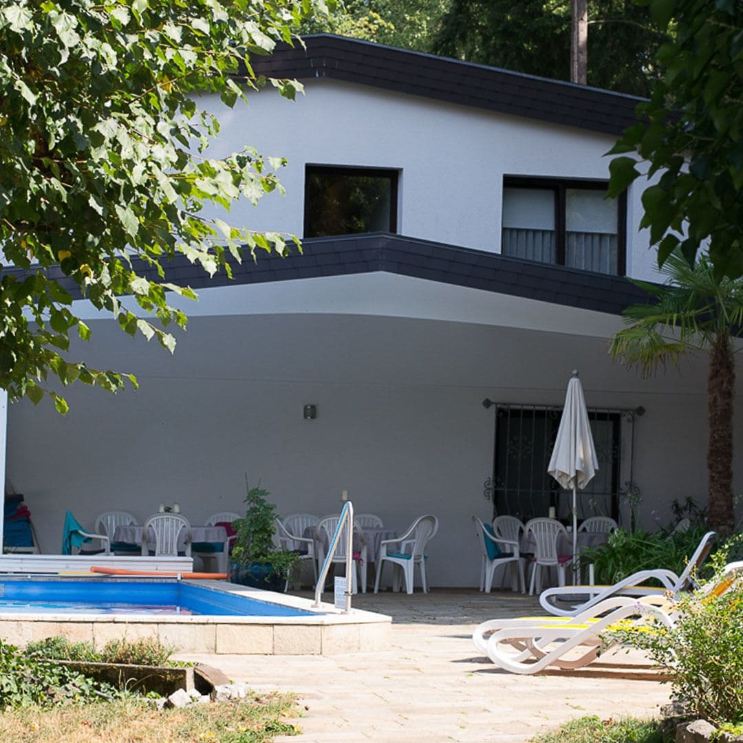 A modern building with a swimming pool, outdoor seating, and a covered patio area.