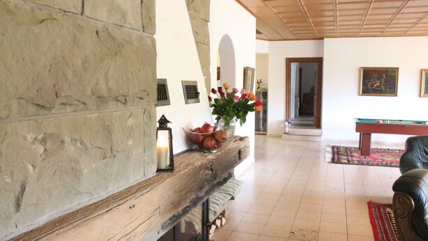 Amplia sala de estar con chimenea de piedra, mesa de billar y un espacio de estar confortable.