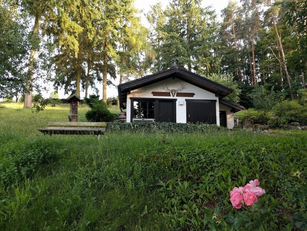 Une cabane rustique avec un toit en pente, une cheminée en pierre et une véranda en bois.