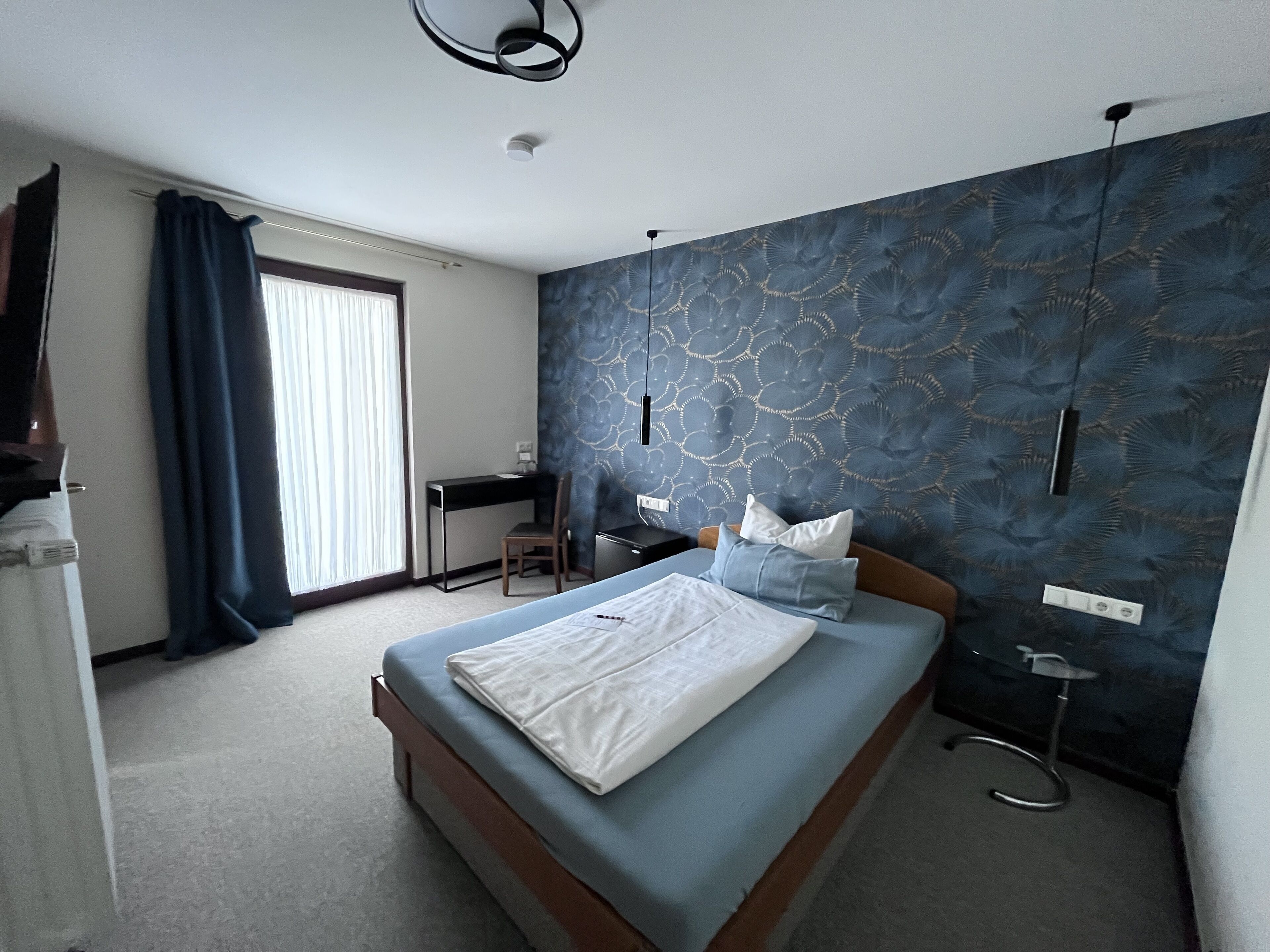 A hotel room with a bed, a desk, and a chair.