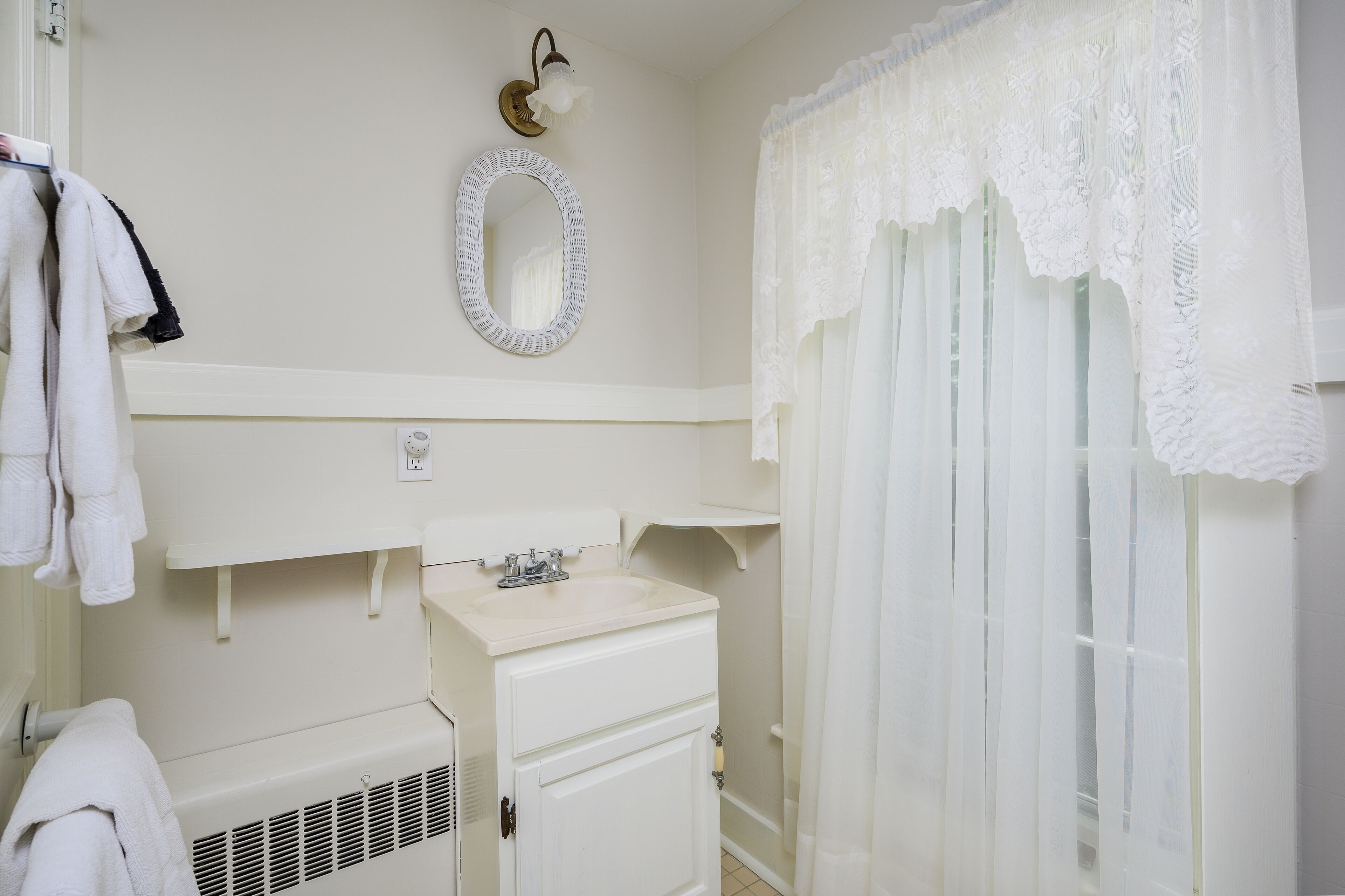 A bathroom with a white sink, mirror, and towel rack.