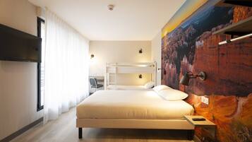 Een hotelkamer met een groot bed, een bureau en een stapelbed.