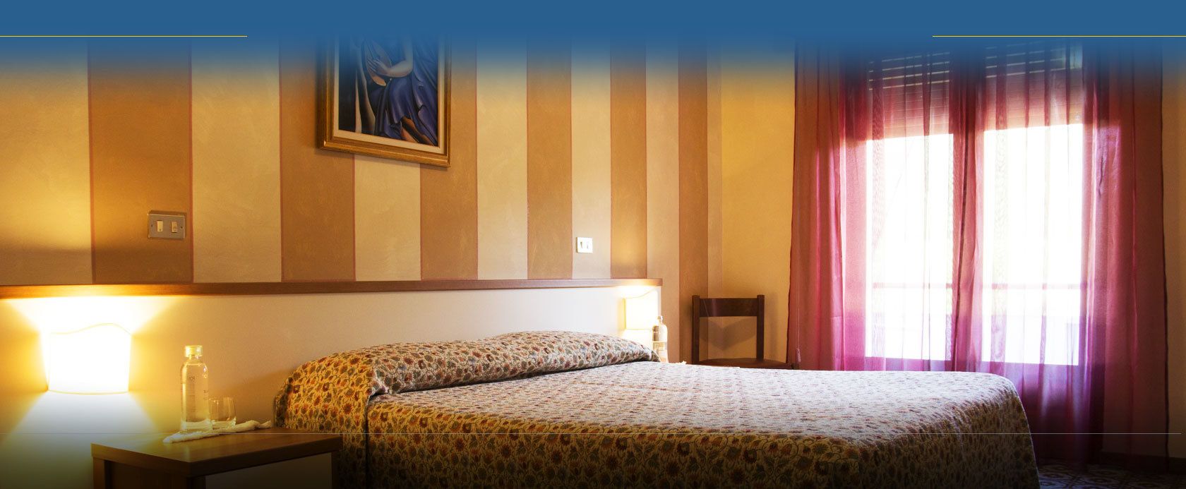 Une chambre d’hôtel avec un lit, une table de chevet, une lampe et un tableau au mur.