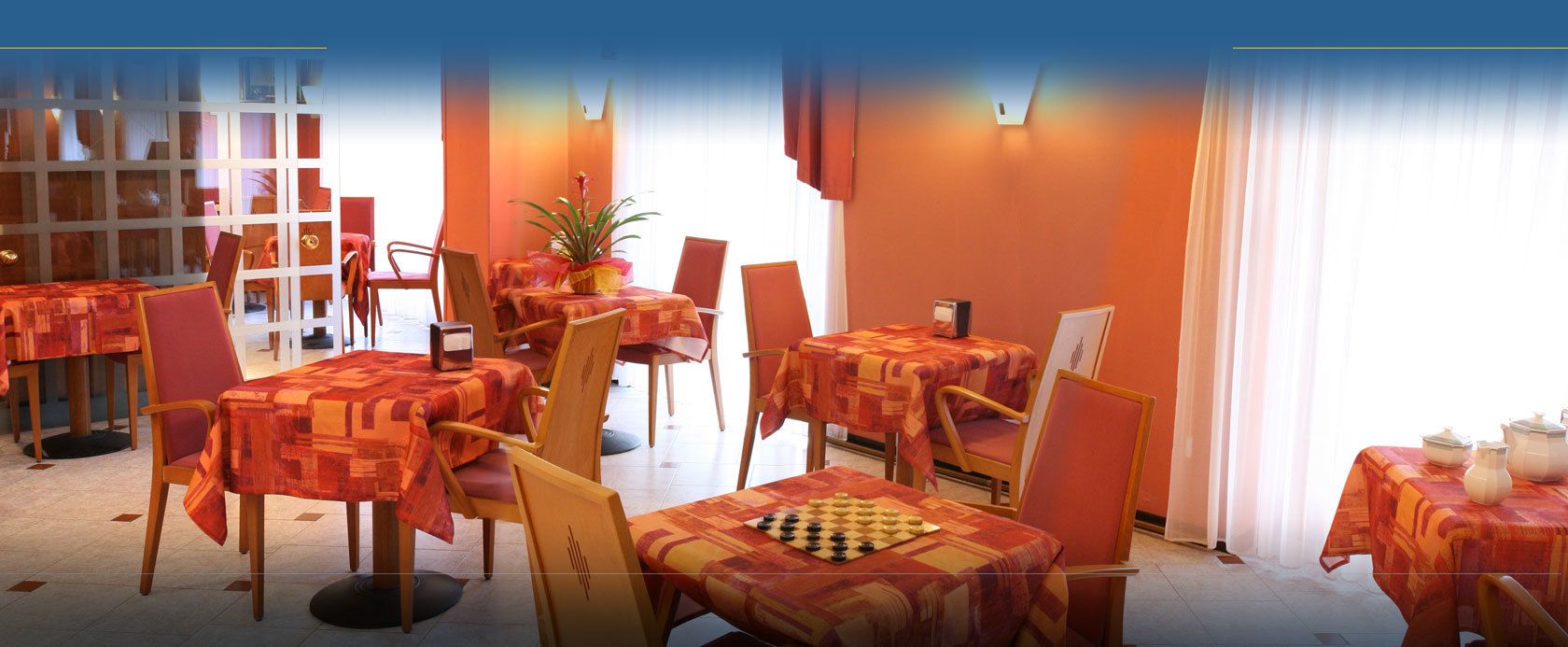 Uma sala de jantar com várias mesas e cadeiras, algumas com jogos de xadrez.