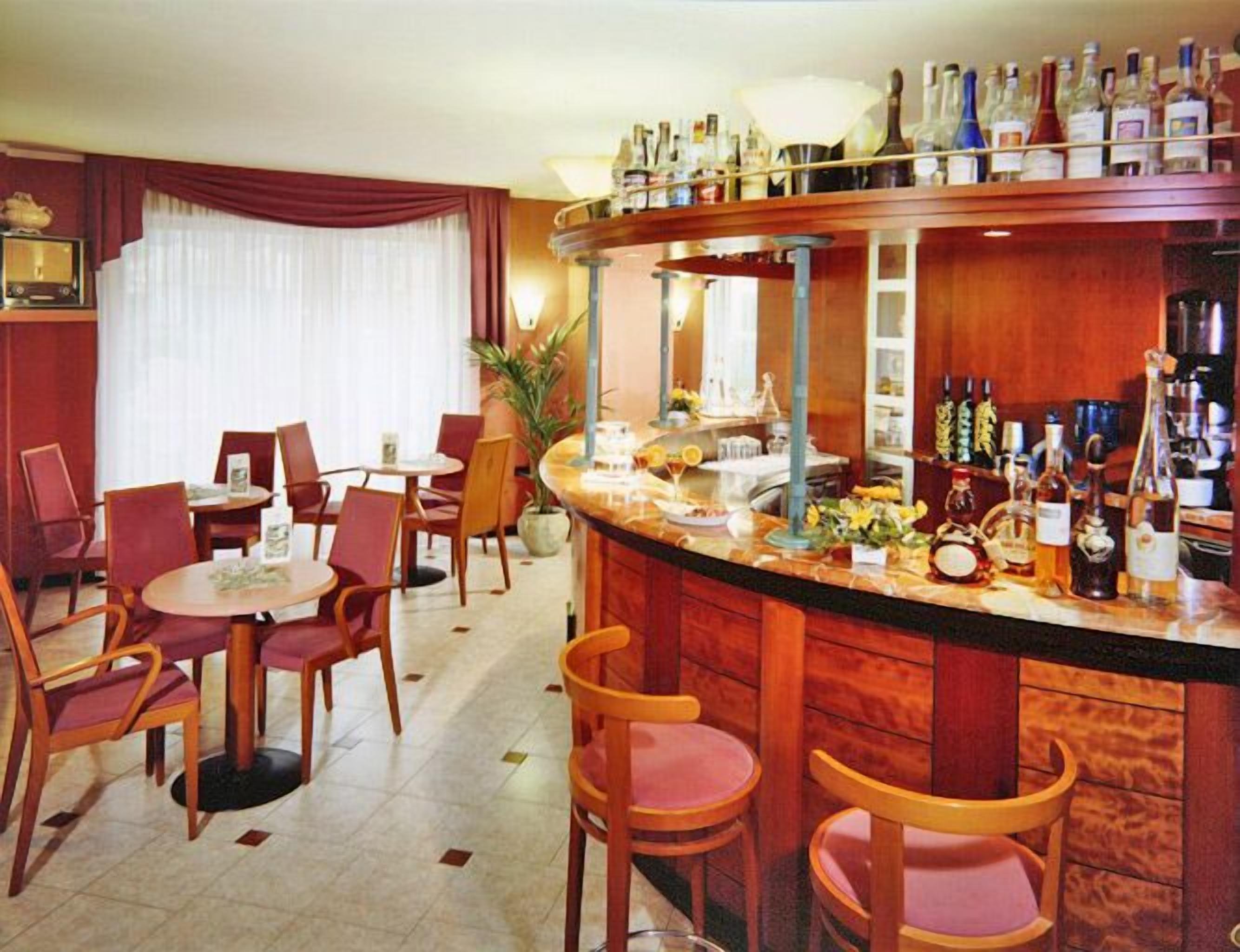 A bar area with a wooden counter, multiple chairs, and a dining area with tables and chairs.