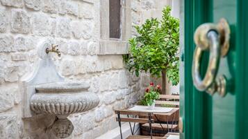 Experience the charm of a traditional entrance with a stone water fountain and a well-maintained green door.