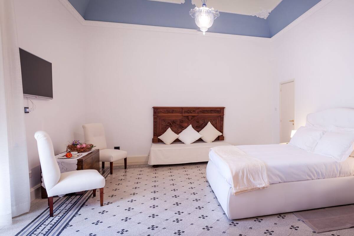 A bedroom with a bed, a chair, a desk, and a television.