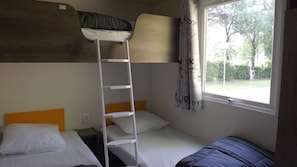 A bunk bed room with a ladder, a window with curtains, and a view of trees. - Camping Plein Soleil - Mobil home (Lourdes)