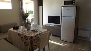 Een eetgedeelte met een tafel gedekt voor twee personen, een koelkast en een televisie op de achtergrond.