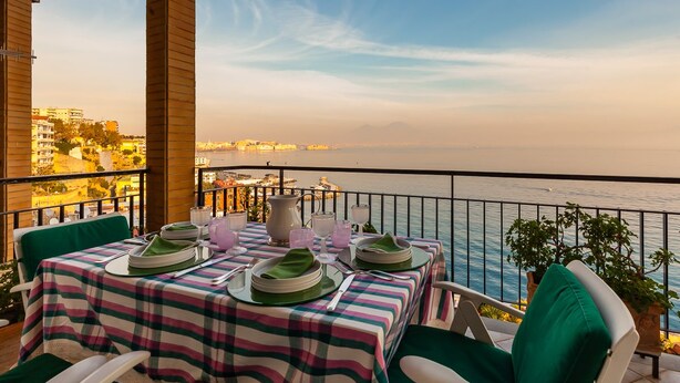 A table set for dining with a view of the sea and cityscape. - O House Posillipo by Napoliapartments (Naples)