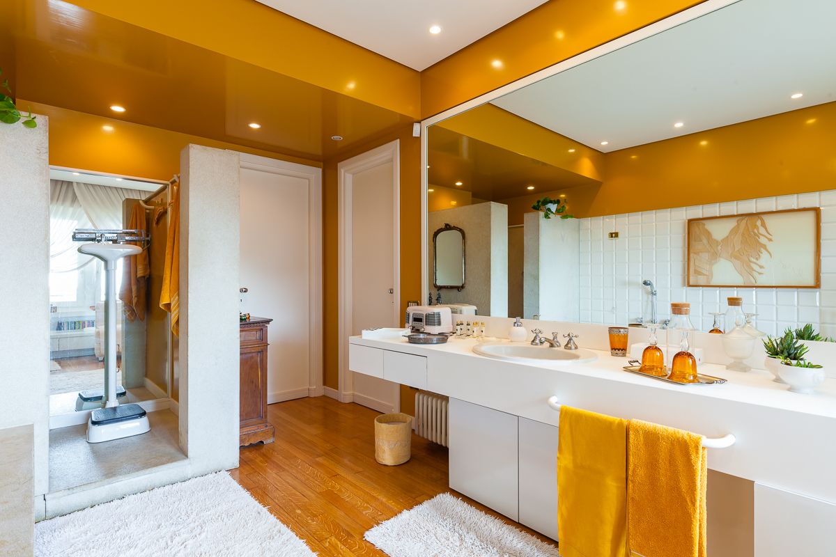 A modern bathroom with a large mirror, white vanity, and a wooden floor.