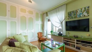 A living room with a green sofa, a glass coffee table, a TV, and a bookshelf. - O House Posillipo by Napoliapartments (Naples)