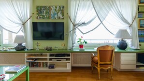 A living room with a green desk, a television, a chair, and a bookshelf. - O House Posillipo by Napoliapartments (Naples)