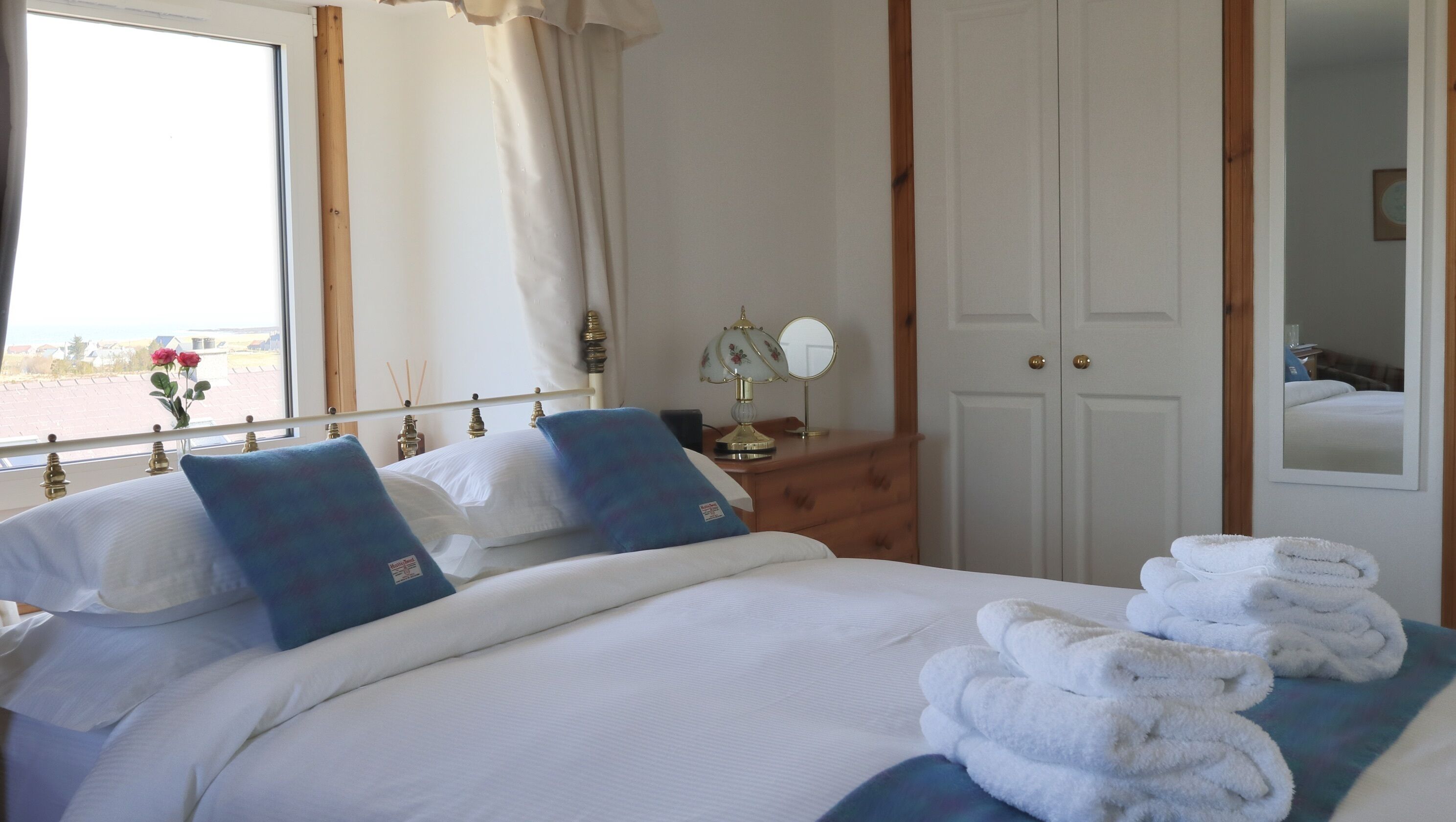A hotel room with a bed, a dresser, a mirror, and a window with curtains.