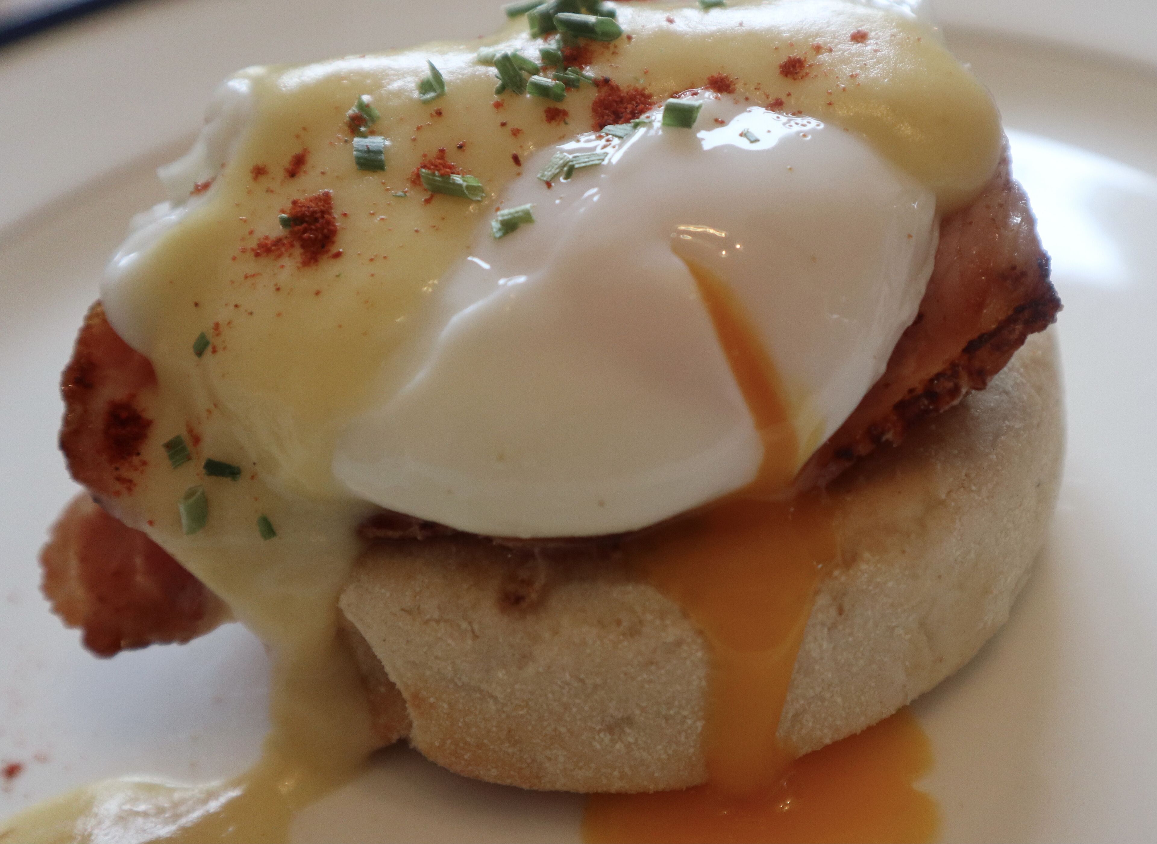 A breakfast dish with poached egg, hollandaise sauce, and chives on toast.