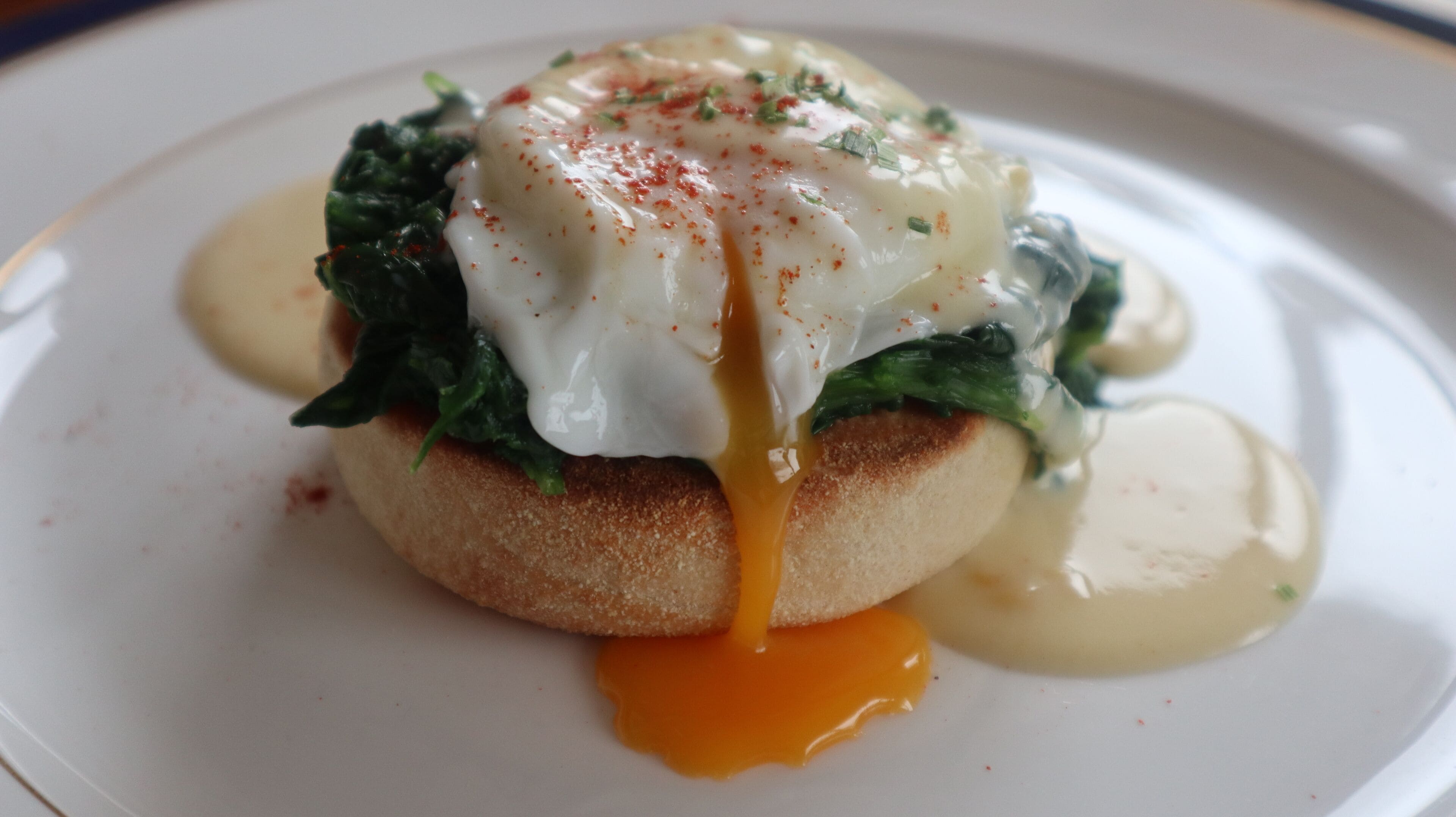 A dish with poached eggs, spinach, and sauce on a plate.