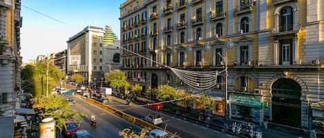 A street view with a building featuring multiple floors, balconies, and a pharmacy on the ground floor.