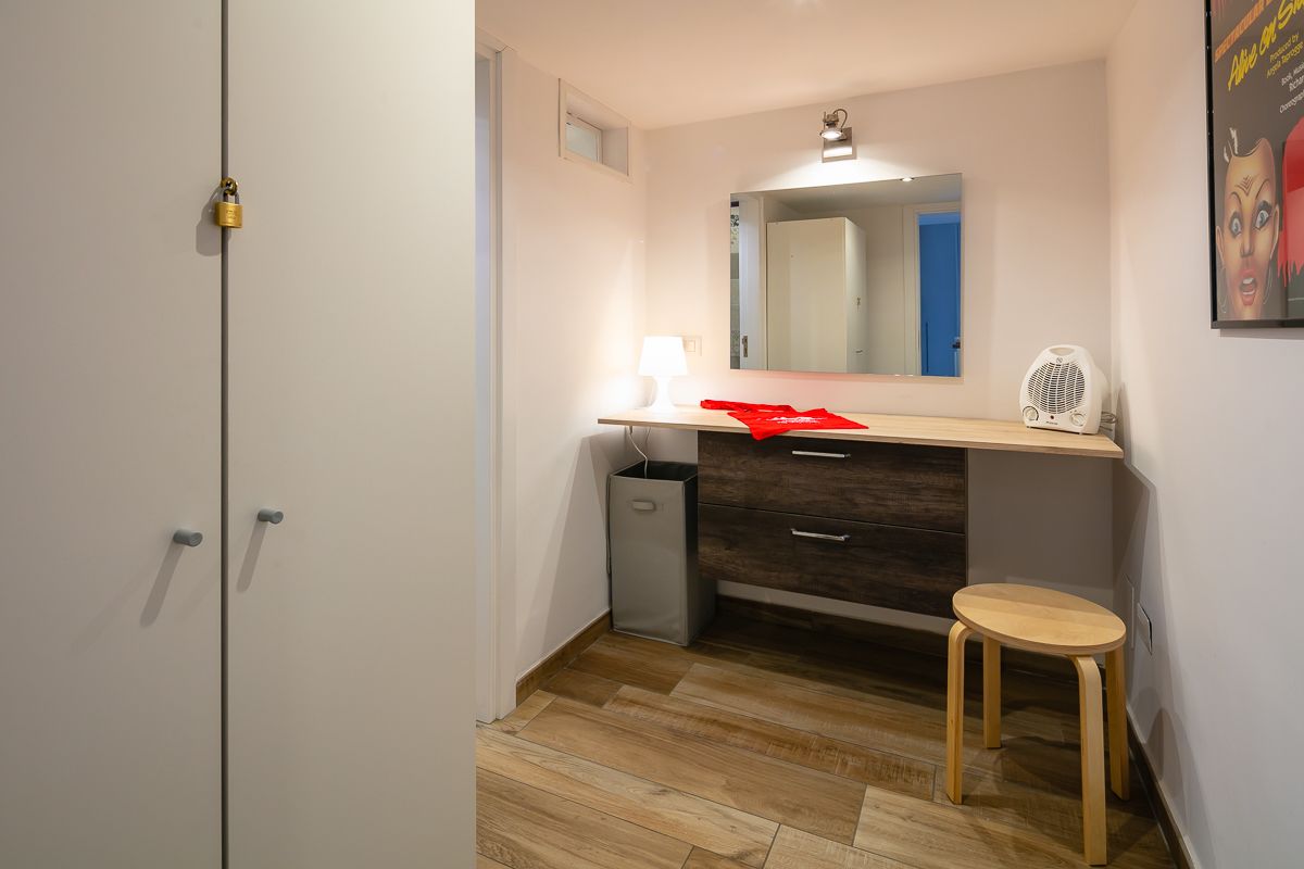 Une salle de bain moderne avec un meuble-lavabo en bois, un miroir, un petit tabouret et une poubelle.