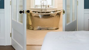 Una stanza con una vasca da bagno grande, un letto e una finestra vista.