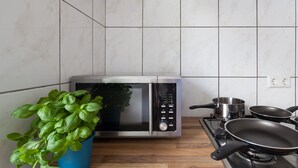A kitchen with a microwave, a stove, and a potted basil plant. - City Apartment Hannover (Hannover)