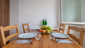 A dining table with four chairs, a fruit bowl with apples and grapes, two wine bottles, and empty glasses. - City Apartment Hannover (Hannover)
