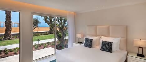 A modern hotel room with a large bed, two bedside tables, and a view of a beach and palm trees.