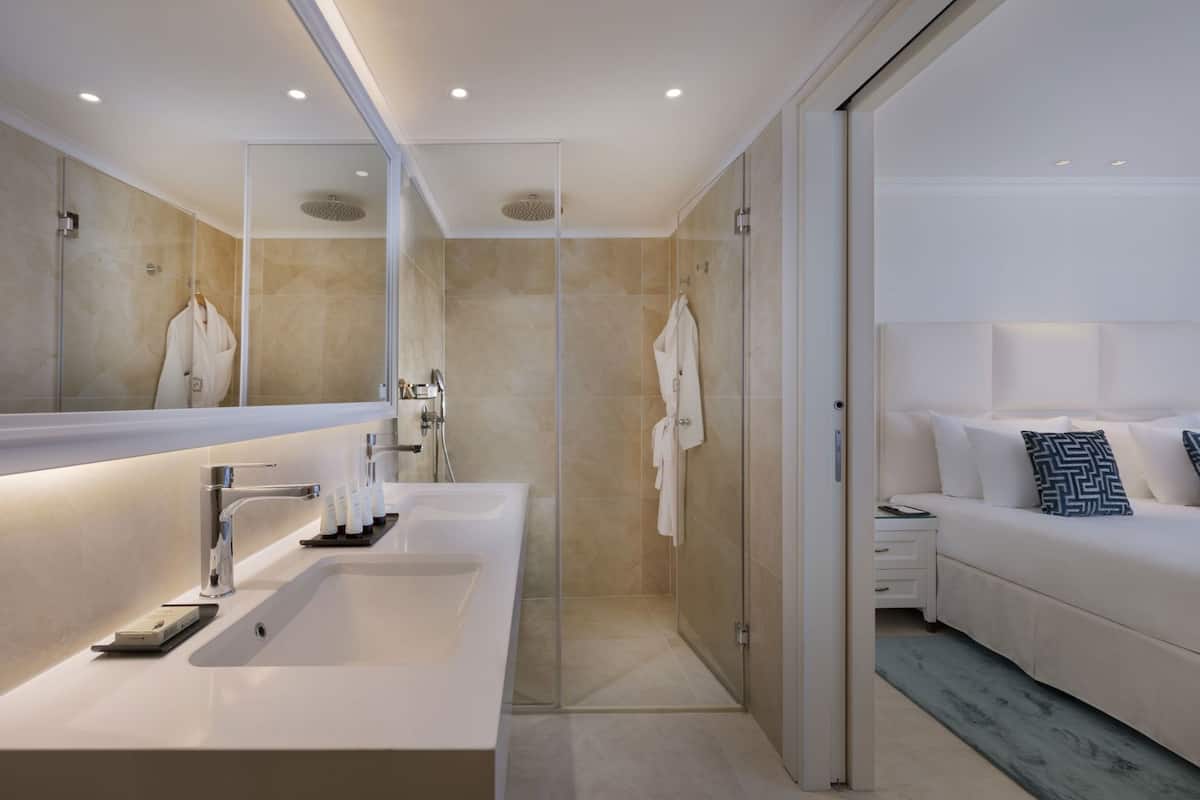 A modern bathroom with a large mirror, a white sink, and a shower area.