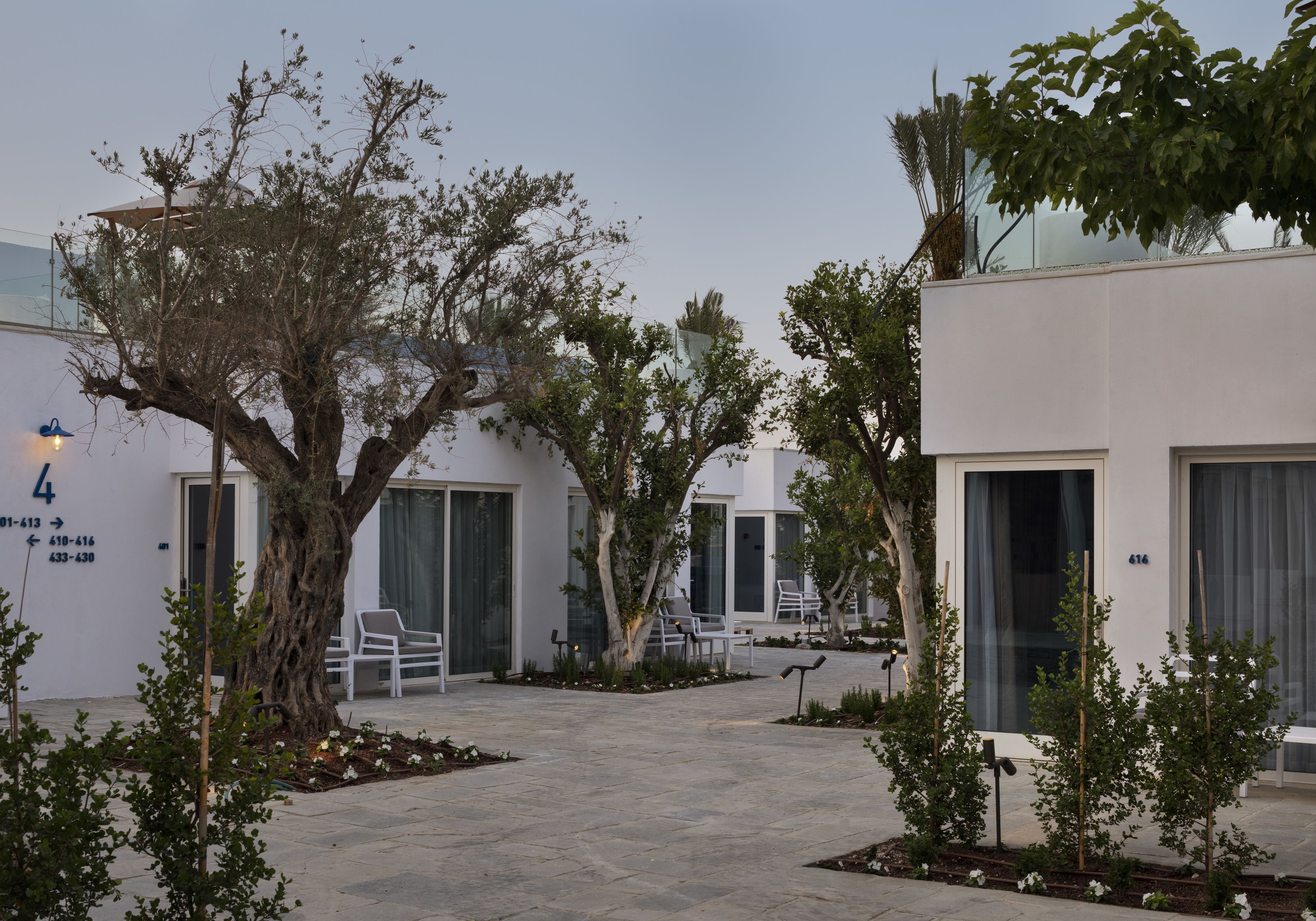 Un edificio moderno con patio, mesas al aire libre y un árbol.