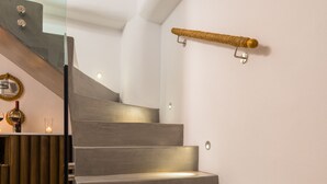 Een moderne trap met een glazen leuning en een decoratief gouden object aan de muur.