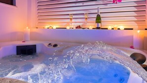 Een bubbelbad met kaarsen en een fles wijn op een plank.