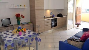 Un espace de vie compact comprenant un coin cuisine, un coin repas et un espace détente avec vue.
