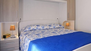 Une chambre à coucher avec un lit, deux tables de chevet et une armoire.