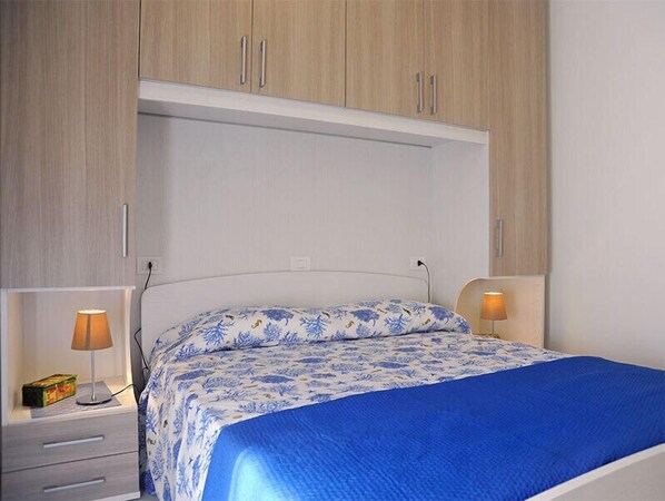 A bedroom with a bed, two bedside tables, and a wardrobe.